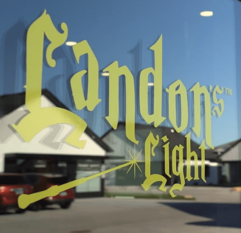 Lime-green “Landon’s Light” logo with a magic wand, displayed on a glass door.